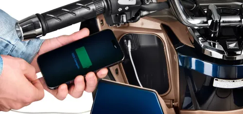 Detalhe da entrada USB-C carregando celular no porta-luvas da PCX